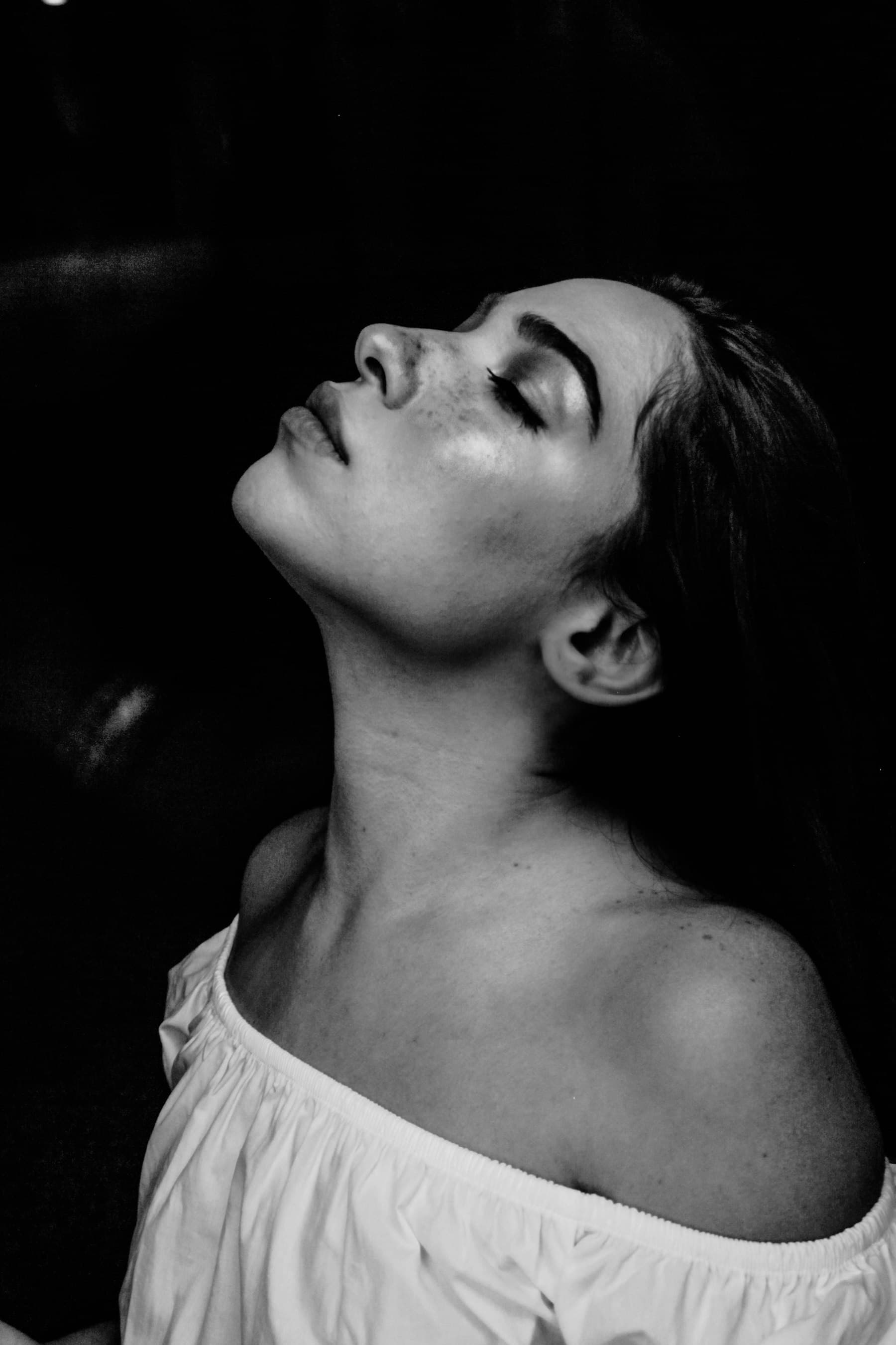 Dramatic black and white studio portrait of a woman looking upward